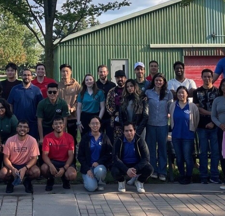 Group of employees at an outdoor summer picnic event, standing under trees.