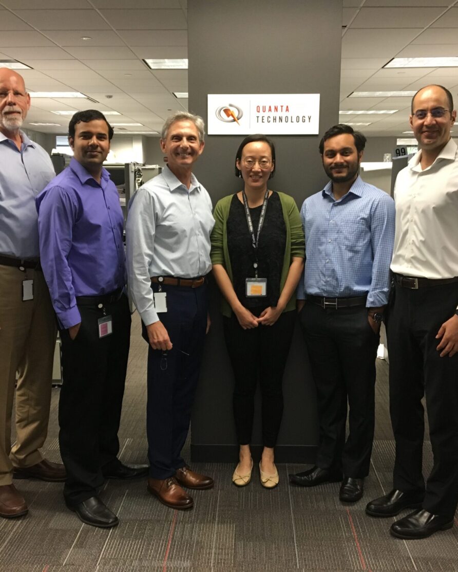 Six employees inside a new Chicago office building with a Quanta Technology plaque.