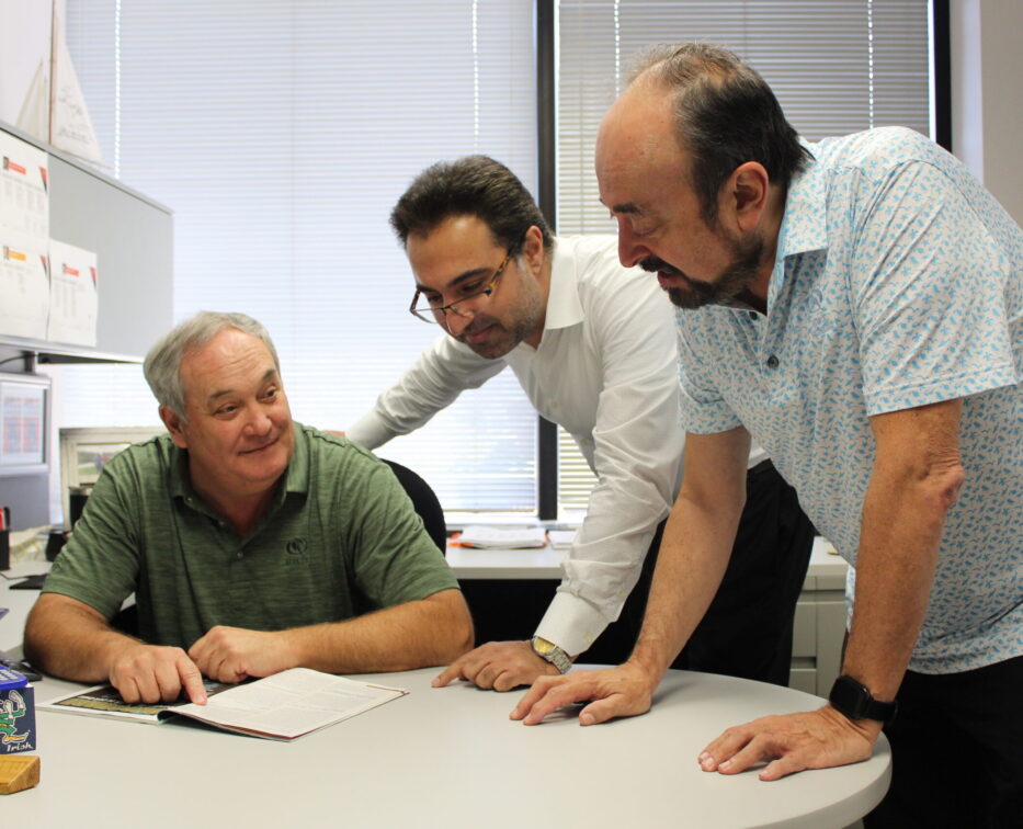 Three employees gathered around a magazine, working together.