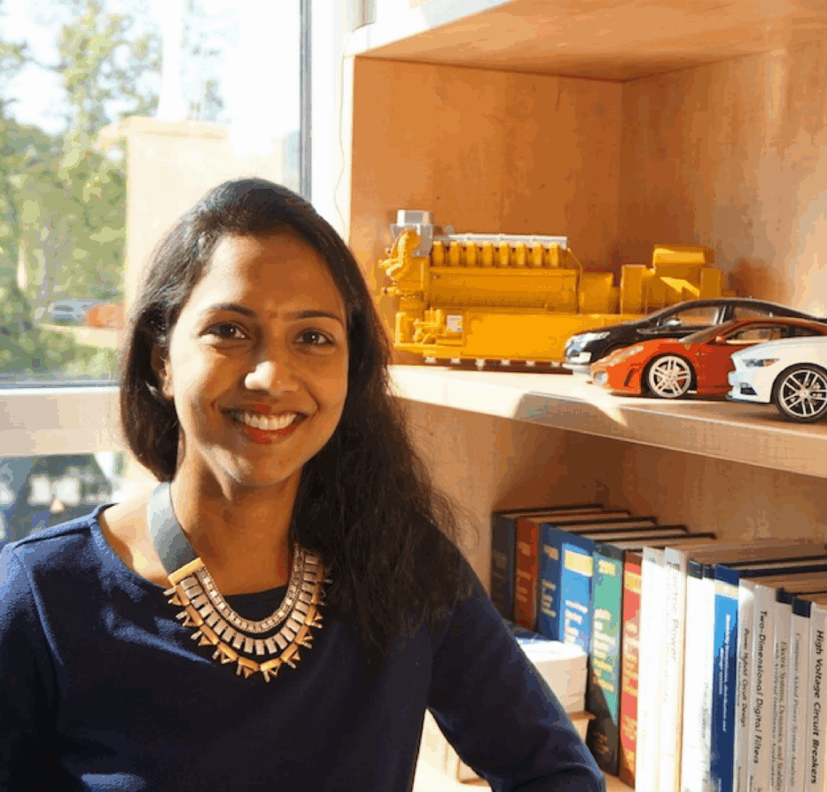 Scholarly woman sitting next to bookshelf in office building.