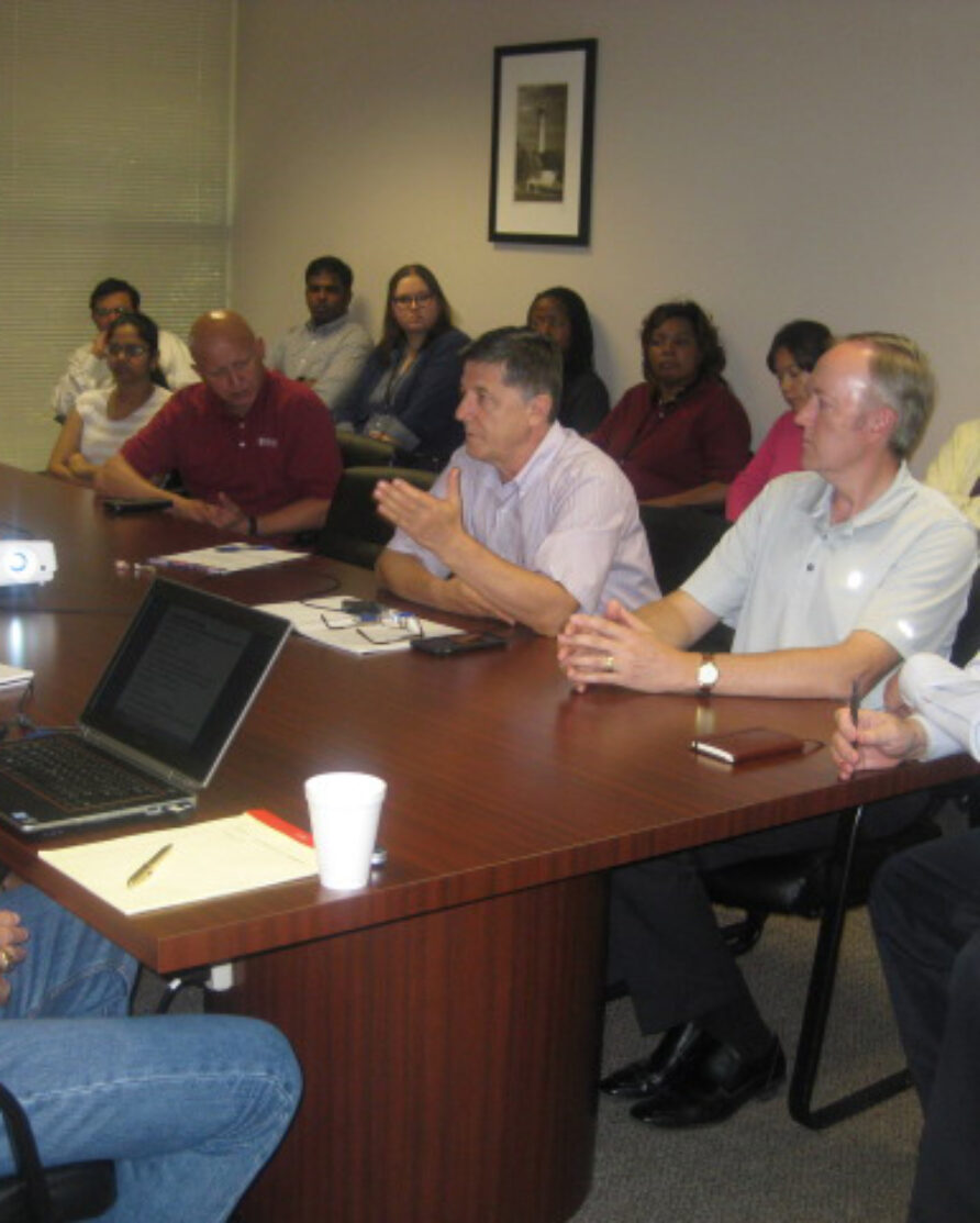 Employees gathered around a wooden table in a conference room.