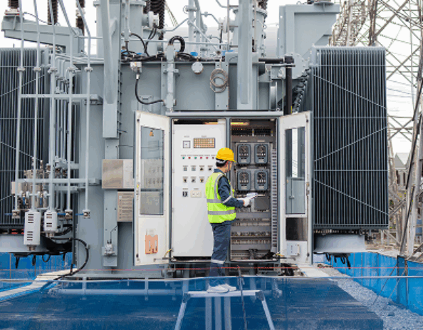 Man in hard hat taking notes at an electric substation.