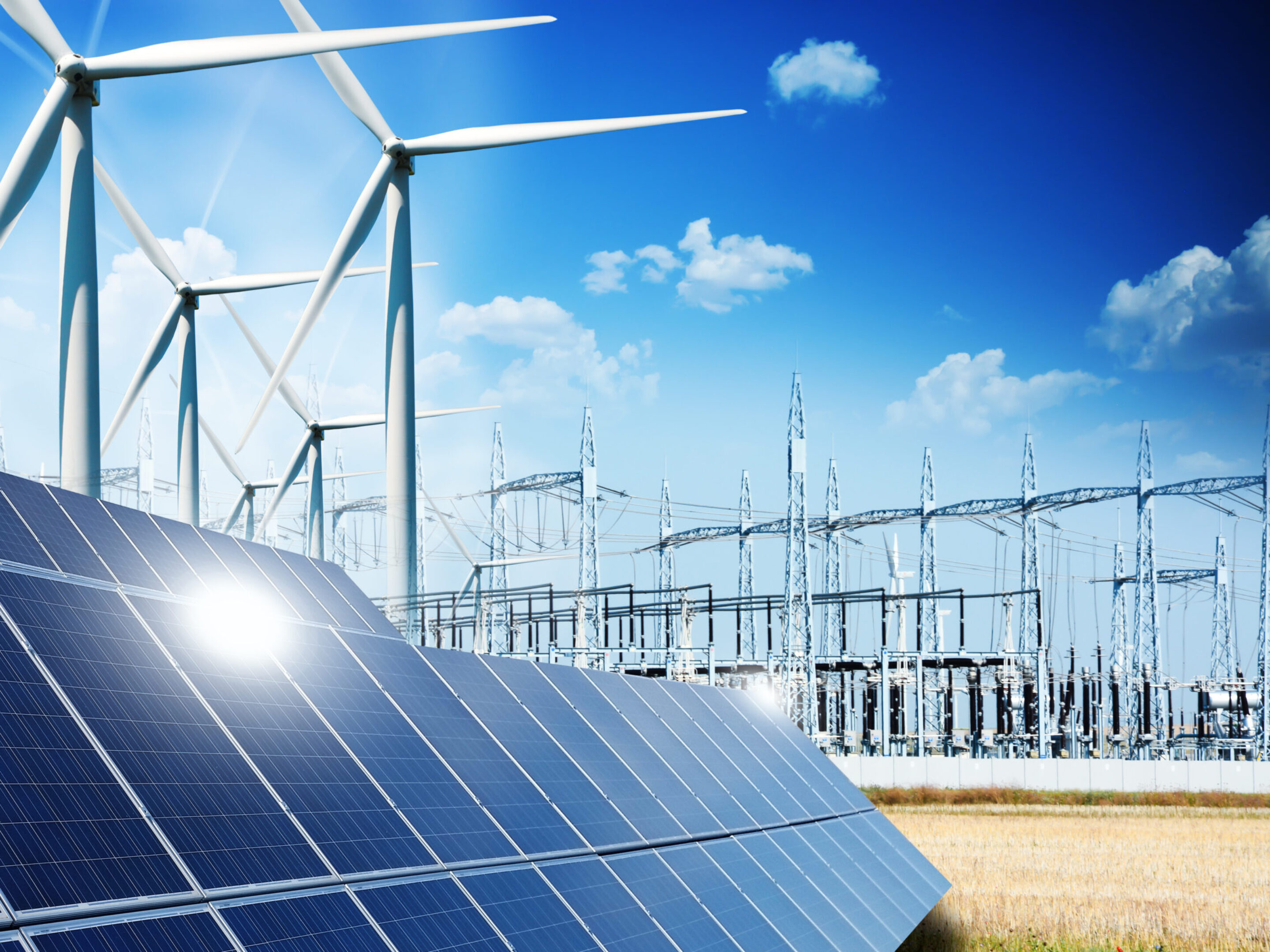 Modern electric grid lines and renewable energy concept, showing windmills and solar panels.