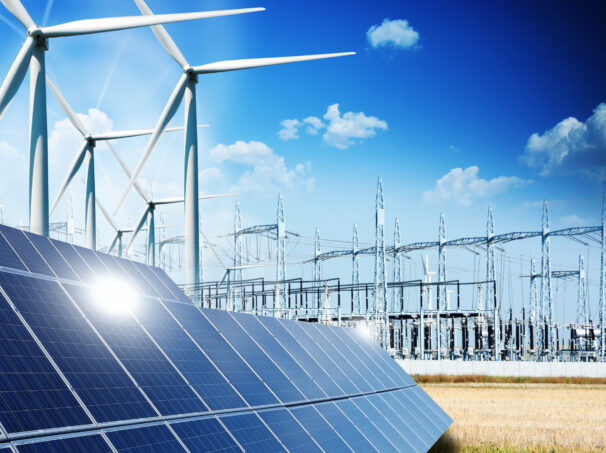 Modern electric grid lines and renewable energy concept, showing windmills and solar panels.