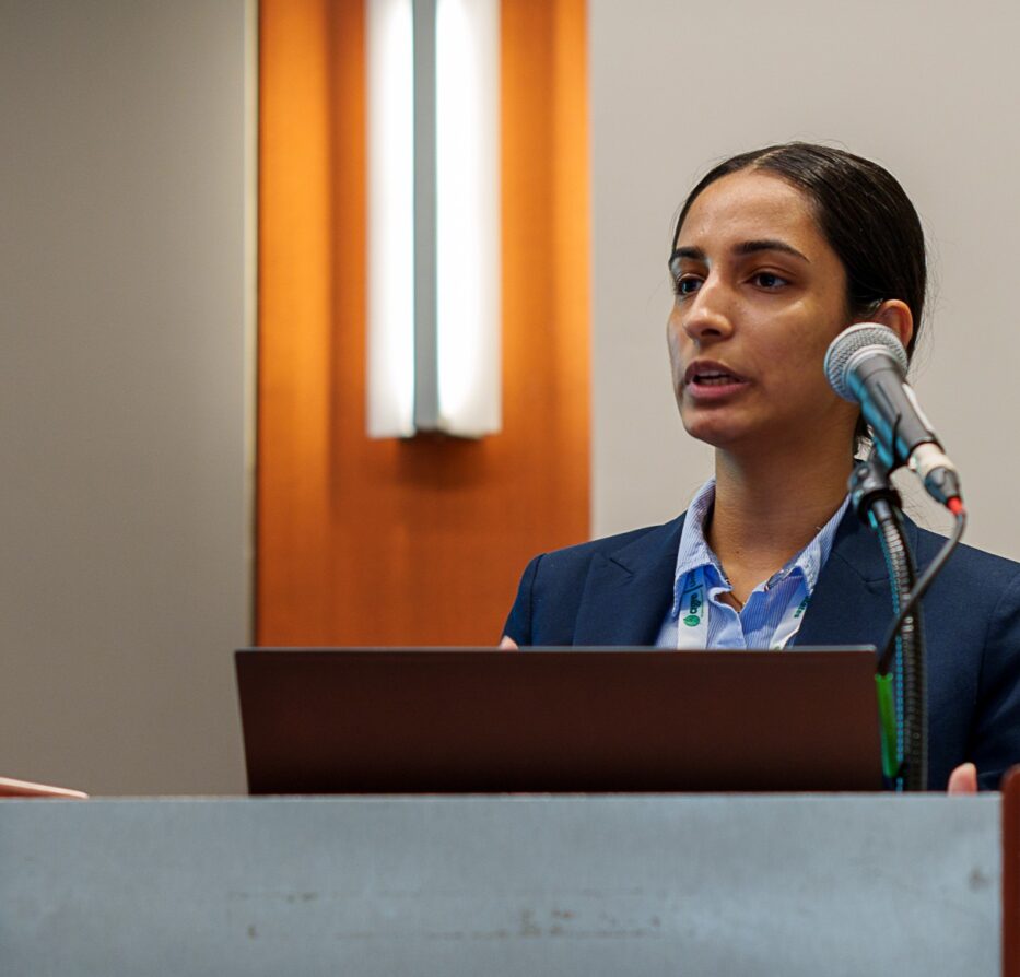 Woman speaking at an indoor podium dressed professionally.