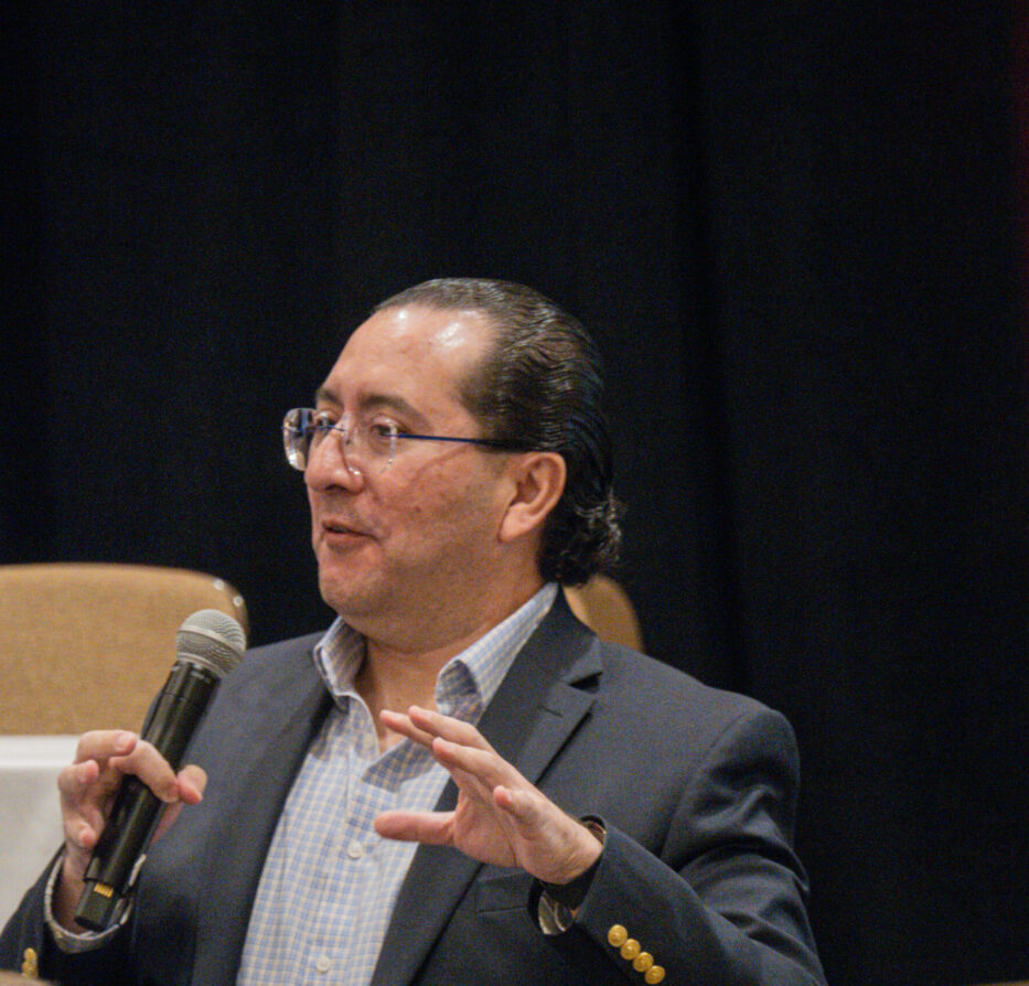 Man speaking into a microphone dressed professionally.