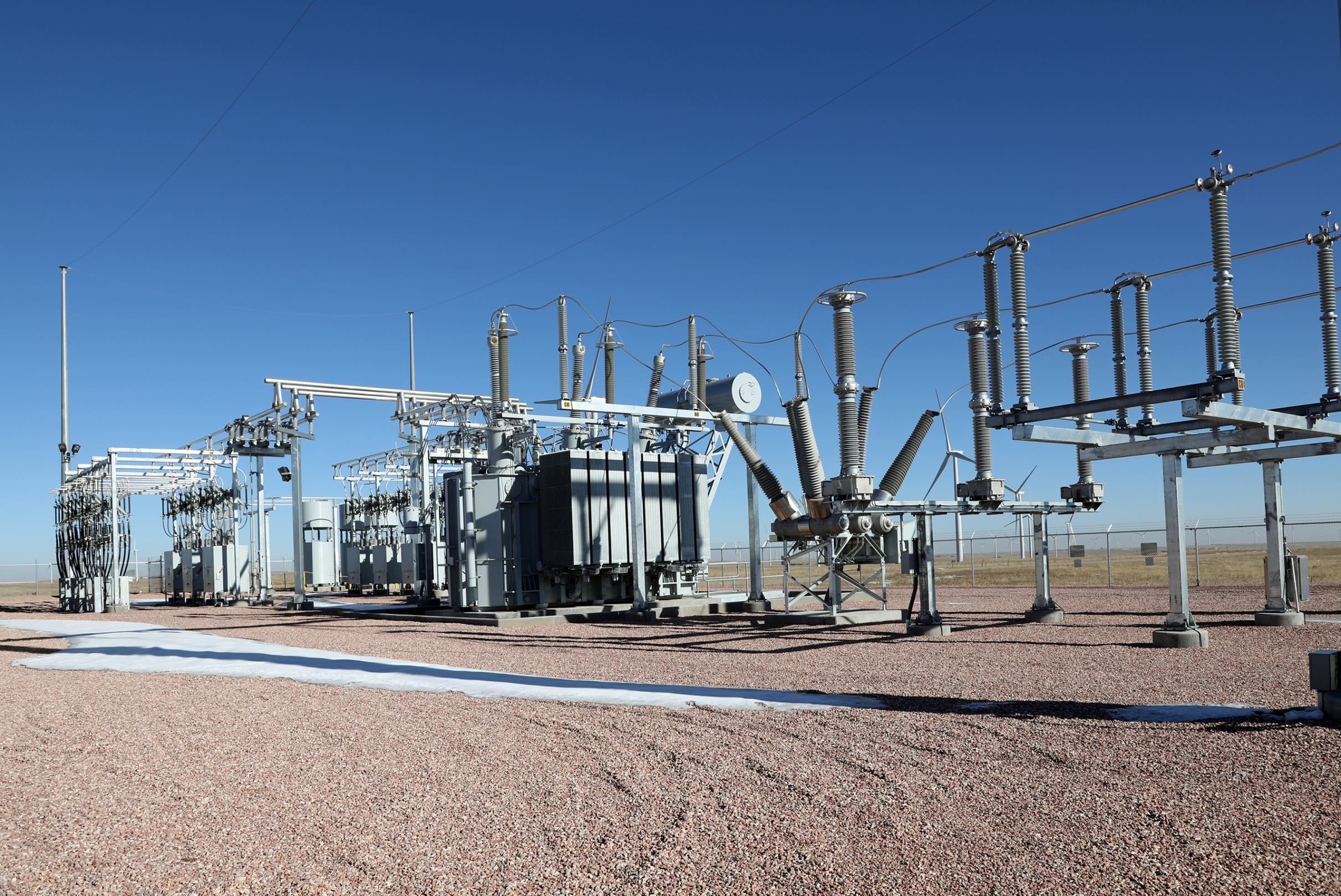 Outdoor high-voltage air-insulated substation with power transformer, circuit breakers, and bus structures.