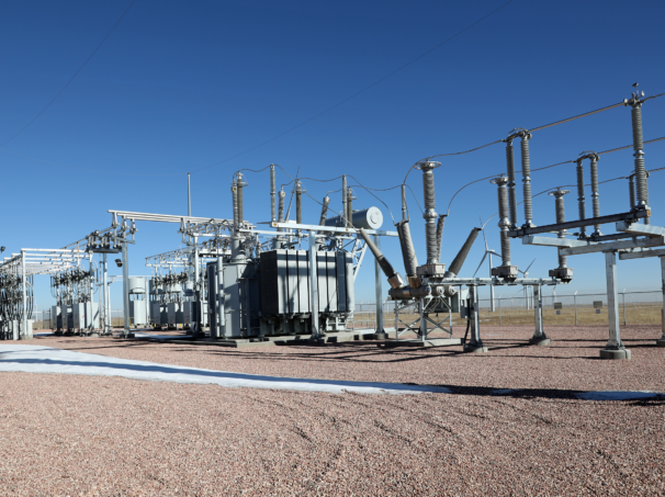 Outdoor high-voltage air-insulated substation with power transformer, circuit breakers, and bus structures.