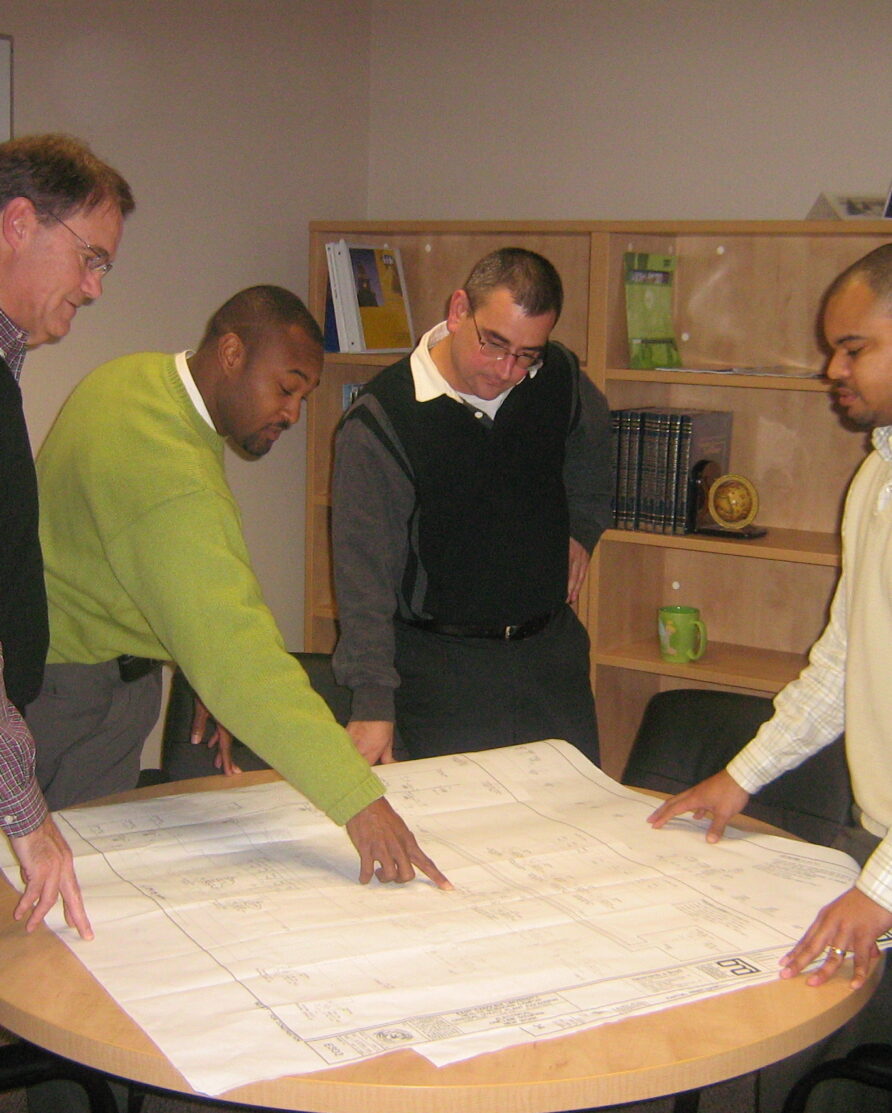 Engineers analyzing diagram on table through teamwork.